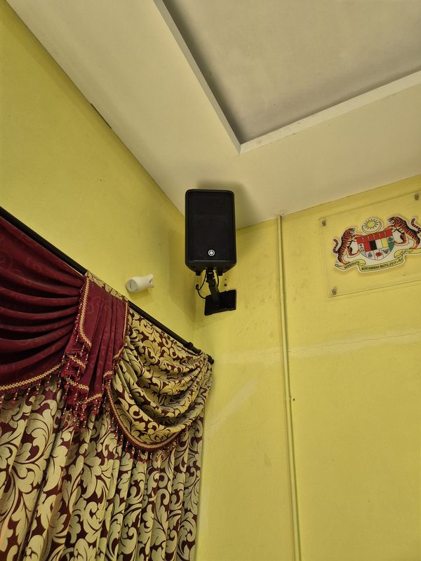 Loudspeaker mounted in the hall corner above the stage curtain