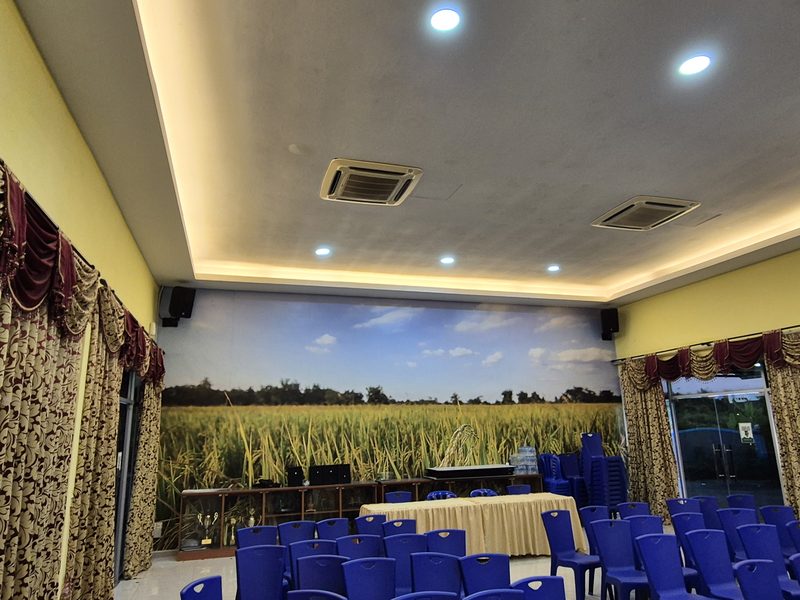 View across the IADA Pulau Pinang seminar hall showing tiered blue seating and distributed wall speakers