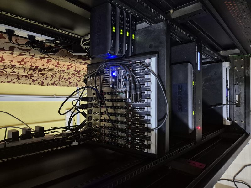 Close-up of the rack showing the patch panel, wireless receivers and amplifier