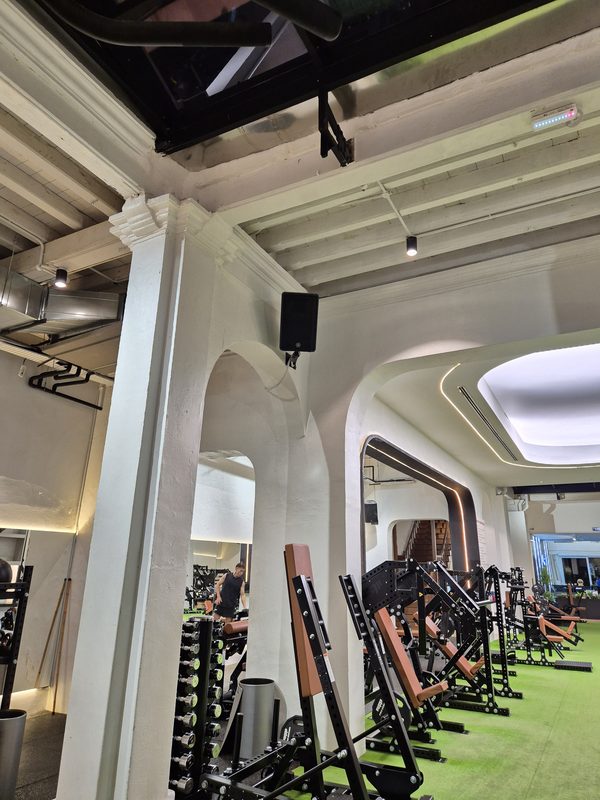 Gym training floor with a loudspeaker mounted on the pillar above the equipment