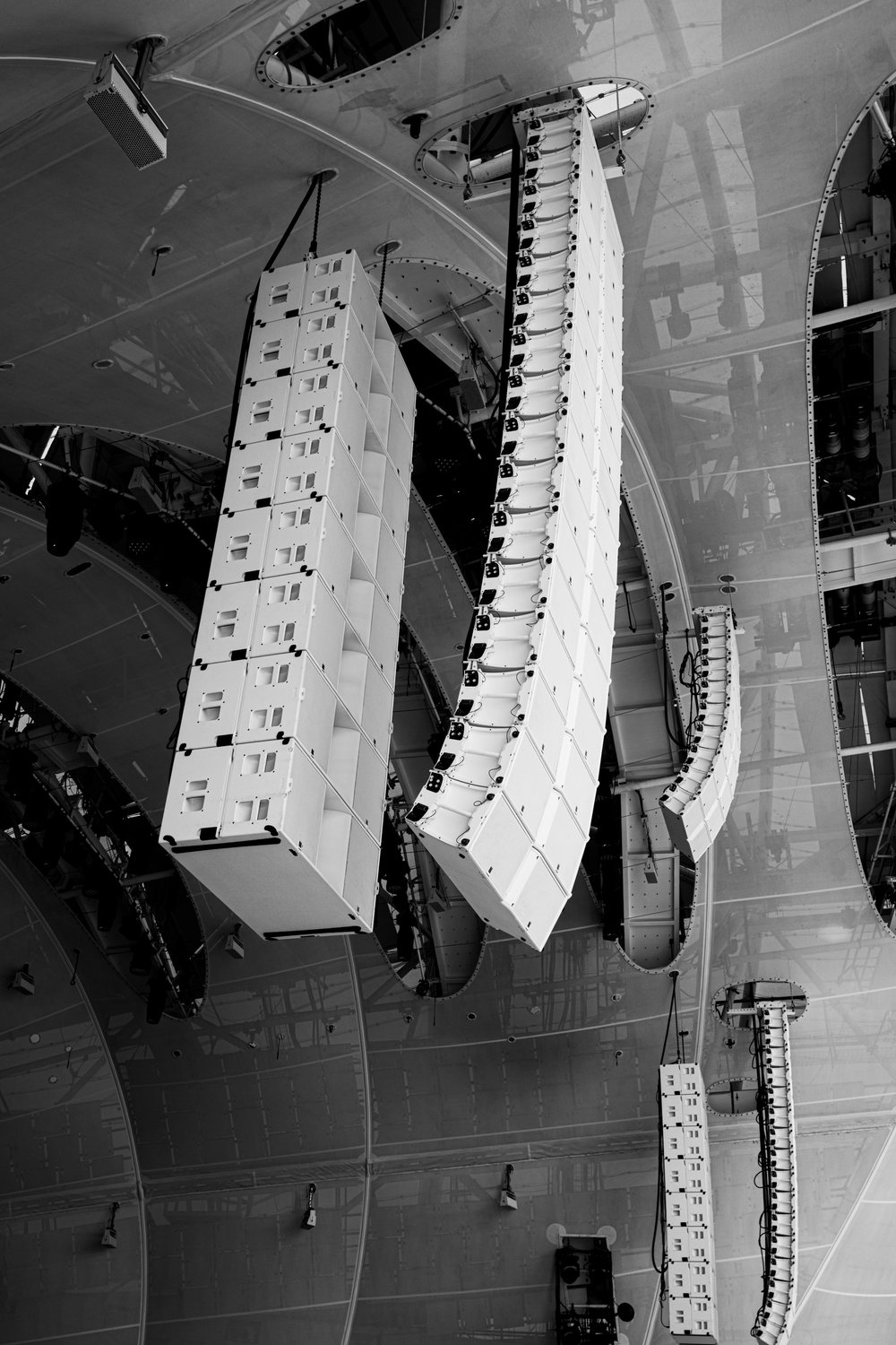 Line array loudspeakers flown from the ceiling structure of a large venue